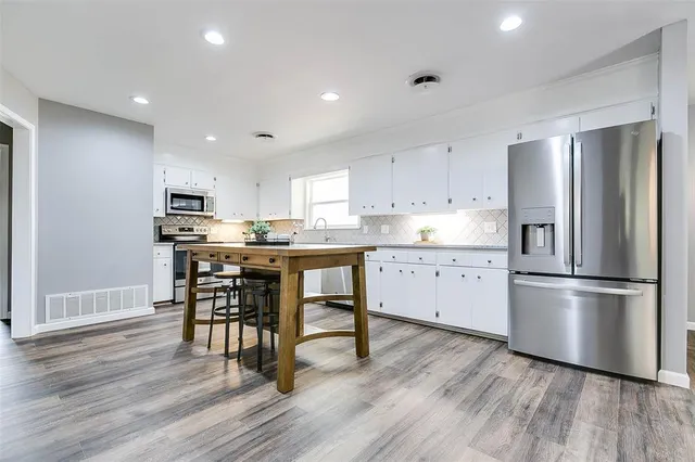 a kitchen with stainless steel appliances a refrigerator a stove top oven and sink
