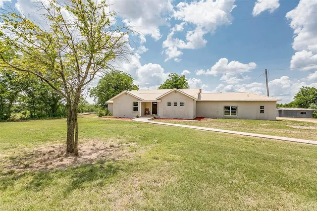 a front view of house with yard and trees in the background