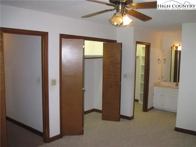 a view of empty room with window and chandelier fan