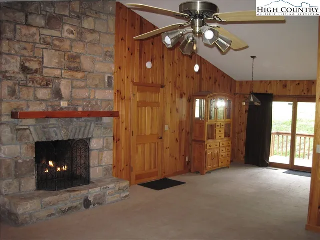 a view of an empty room with chandelier fan and fire place