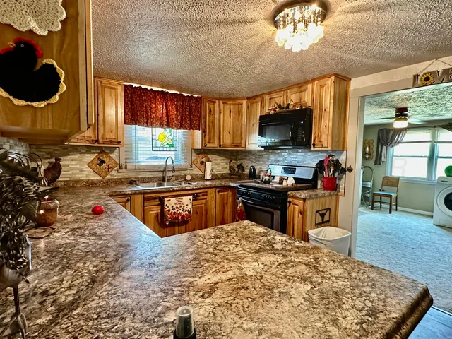 a kitchen with kitchen island granite countertop a stove a sink and a microwave