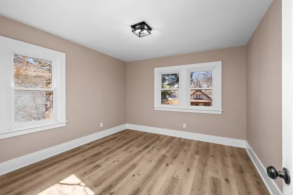 a view of empty room with window and wooden floor