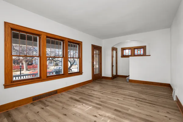 a view of an empty room with window and wooden floor