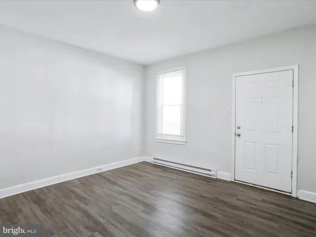 an empty room with wooden floor and window