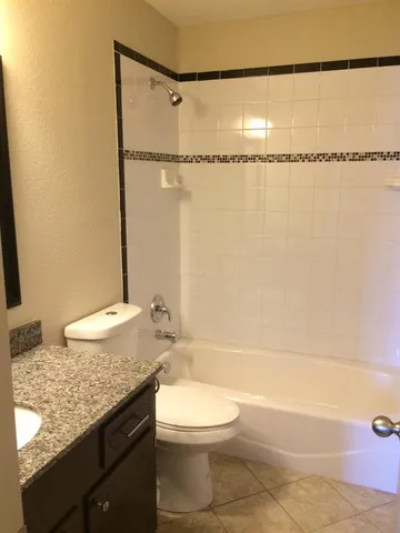 a bathroom with a granite countertop sink mirror vanity and toilet