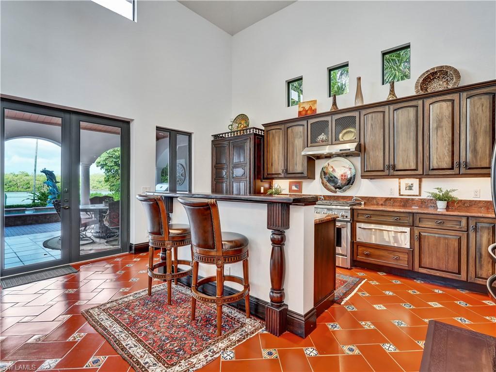 2535 Tarpon Road Naples, FL 34102 - Photo 14 of 50 Spacious interior featuring a large dining area with a wrought iron chandelier, terracotta-style flooring with decorative tile accents, and multiple glass French doors
