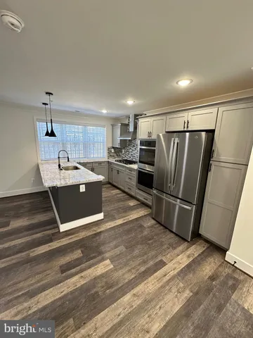 a kitchen with stainless steel appliances kitchen island granite countertop a refrigerator and a sink