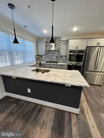 a kitchen with kitchen island a counter space a sink appliances and cabinets