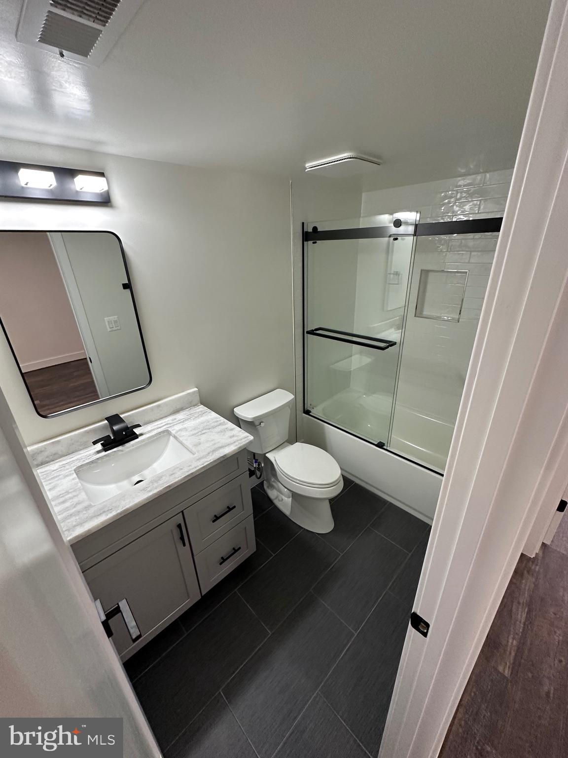 3210 8th Street Southeast, Unit 1 Washington, DC 20032 - Photo 6 of 14 a bathroom with a granite countertop sink a toilet and a mirror