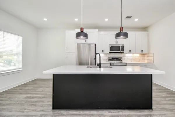 a kitchen with kitchen island stainless steel appliances a sink and a wooden floor