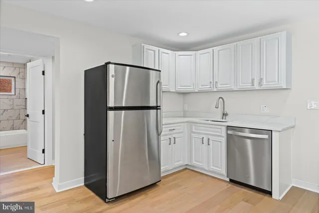 a kitchen with stainless steel appliances granite countertop a refrigerator sink and white cabinets