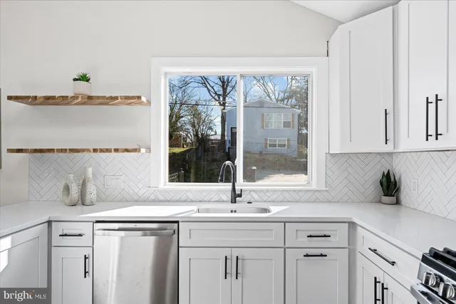 a kitchen with stainless steel appliances white cabinets and a window