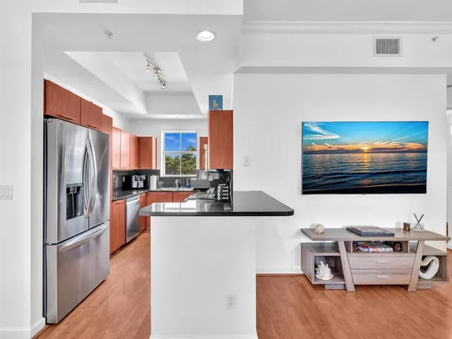 a kitchen with stainless steel appliances kitchen island granite countertop a refrigerator and a stove top oven