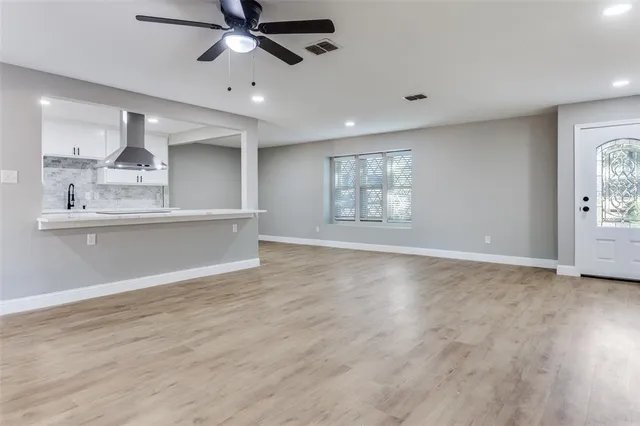 a view of an empty room with a window and wooden floor