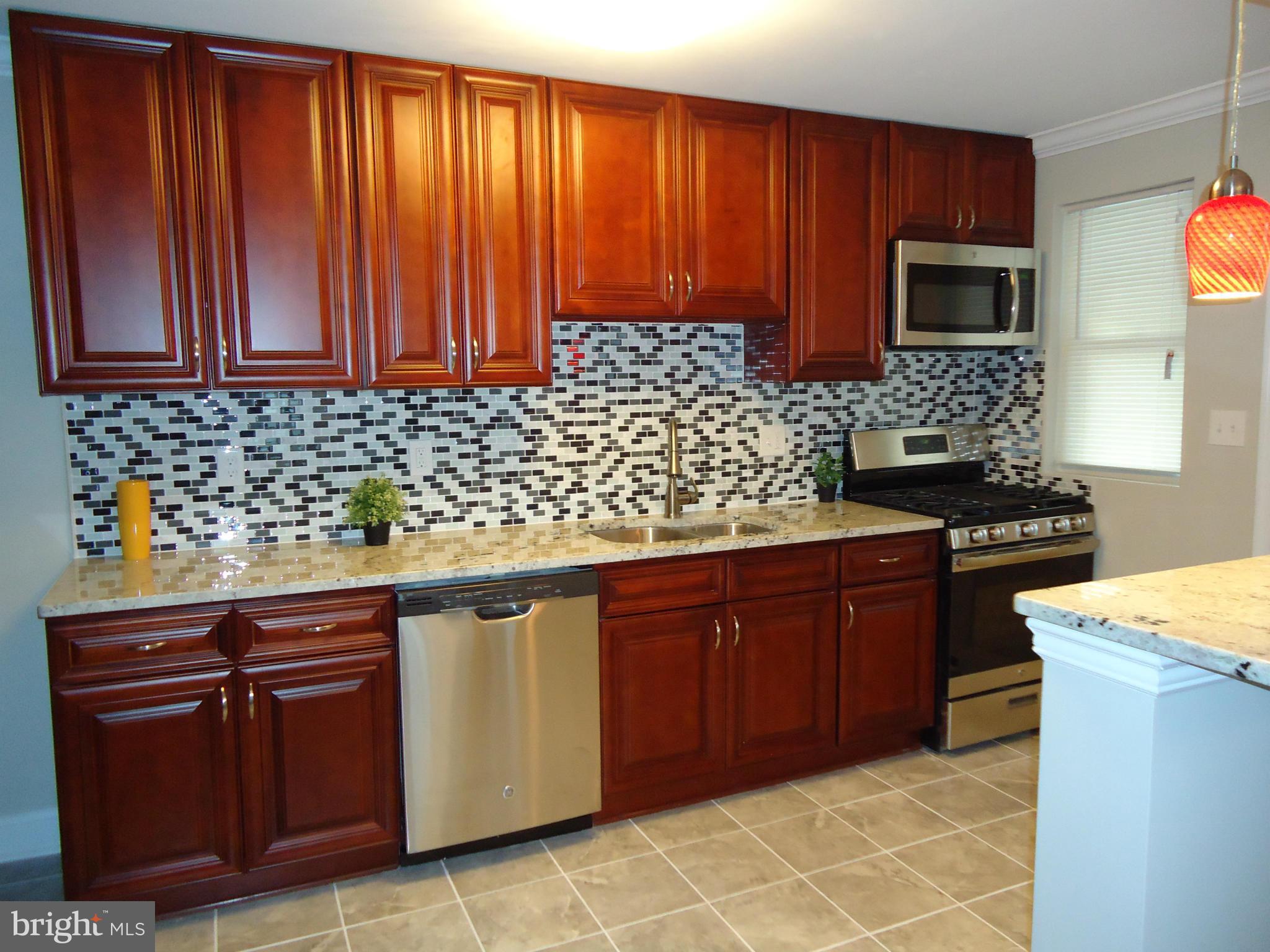 5720 Maplehill Road Baltimore, MD 21239 - Photo 7 of 25 a kitchen with stainless steel appliances granite countertop wooden cabinets a stove top oven with wooden floor