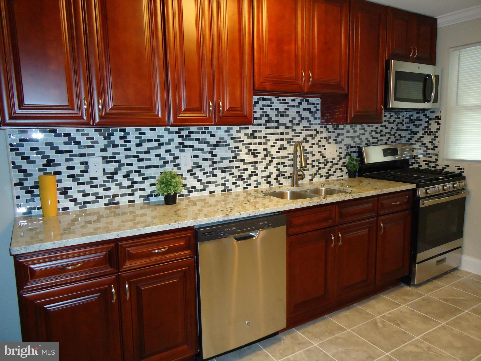5720 Maplehill Road Baltimore, MD 21239 - Photo 9 of 25 a kitchen with granite countertop stainless steel appliances a stove sink and cabinets