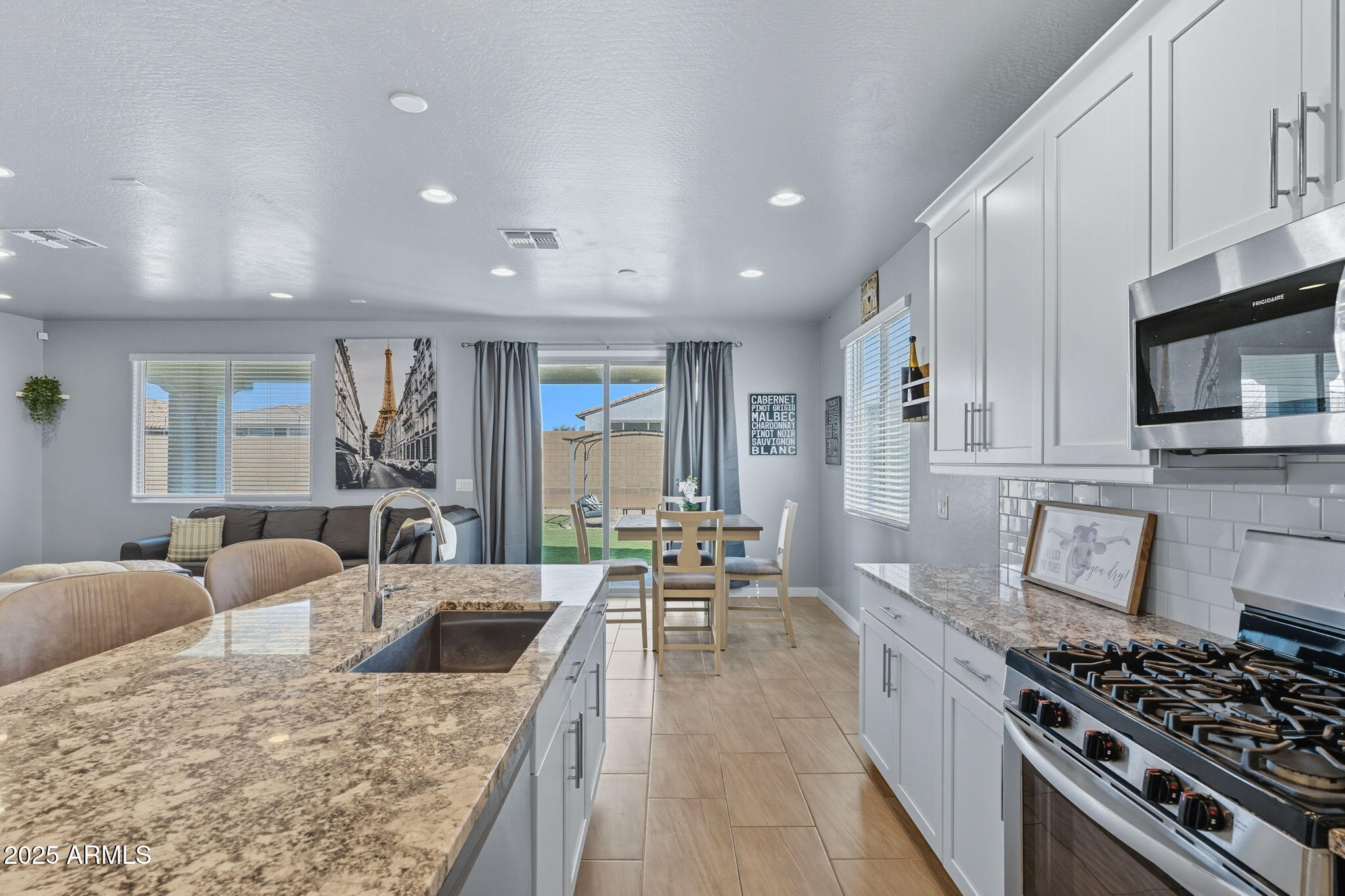 12404 East Soloman Road Gold Canyon, AZ 85118 - Photo 15 of 47 a kitchen with stainless steel appliances kitchen island granite countertop a stove a sink dishwasher a dining table and chairs with wooden floor