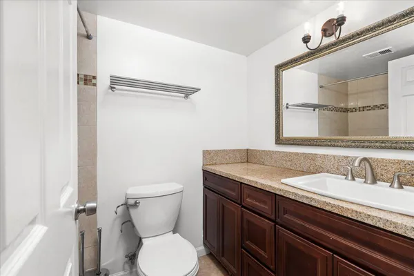a bathroom with a granite countertop toilet sink and mirror