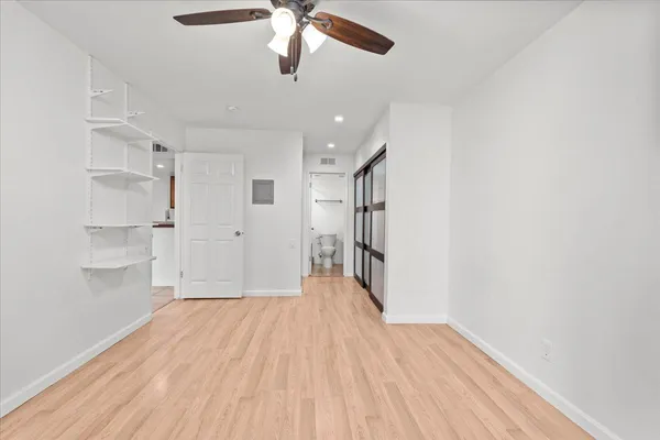 an empty room with wooden floor closet and windows