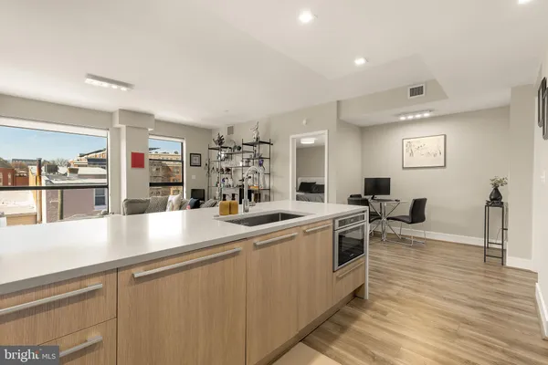 a kitchen with stainless steel appliances a sink and wooden floor