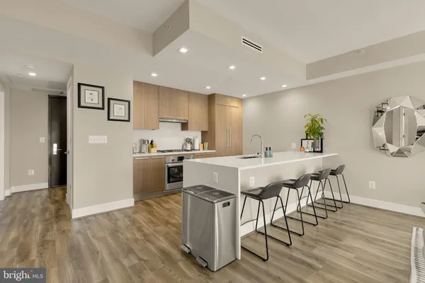 a kitchen with stainless steel appliances a dining table chairs refrigerator and sink