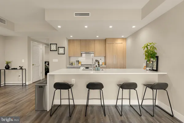 a kitchen with stainless steel appliances granite countertop a dining table chairs and white wooden cabinets