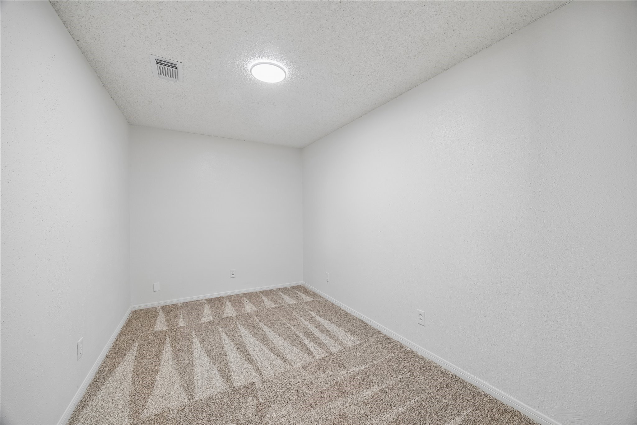 631 Lexington Square Humble, TX 77338 - Photo 17 of 22 This photo shows a small, windowless room with white walls and beige carpet. It has a ceiling light providing ample illumination, making it suitable for use as a storage area or a compact office space.