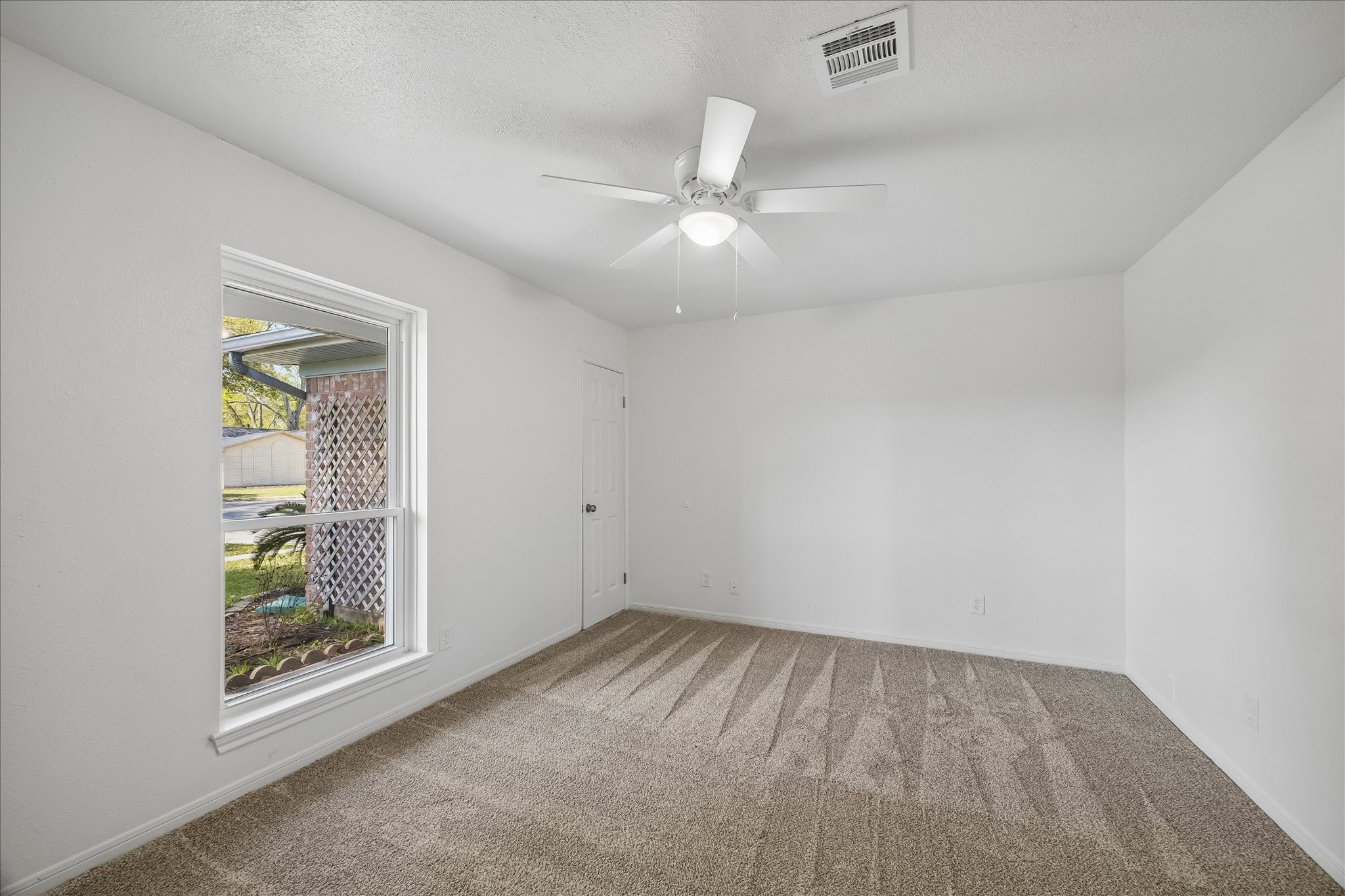 631 Lexington Square Humble, TX 77338 - Photo 18 of 22 Bright, freshly painted room with new carpet, a ceiling fan, and a large window providing natural light.