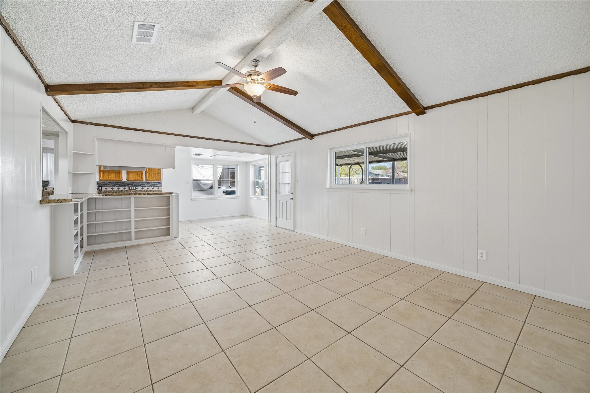 631 Lexington Square Humble, TX 77338 - Photo 2 of 22 This inviting family room boasts high ceilings with rustic beams, a ceiling fan, and large windows that flood the space with natural light, complemented by an open layout perfect for entertaining.