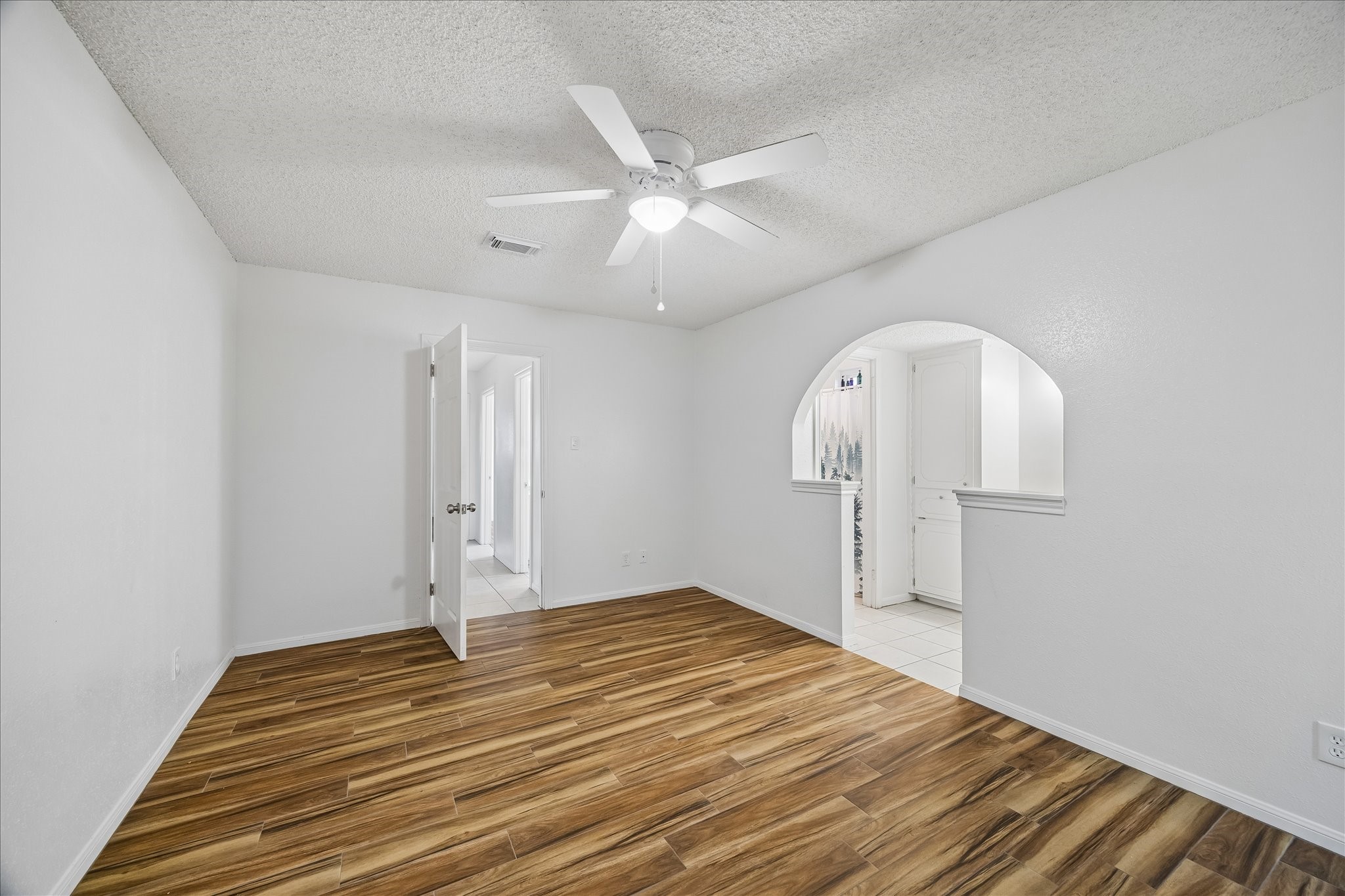 631 Lexington Square Humble, TX 77338 - Photo 4 of 22 This inviting dining room features elegant wood flooring, a modern ceiling fan, and a charming arched entryway that leads seamlessly into the kitchen, creating a perfect space for family gatherings and entertaining.