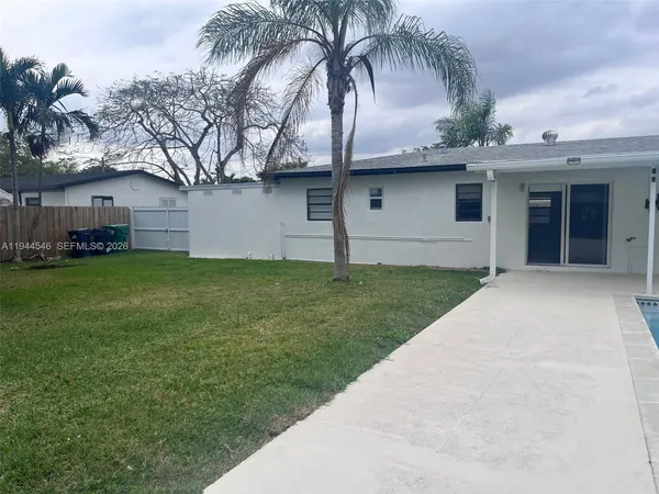 front view of a house with a yard and palm trees