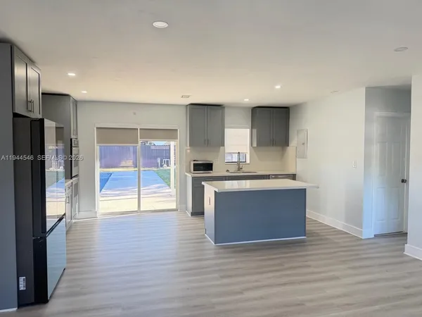 a large kitchen with stainless steel appliances granite countertop a refrigerator and a sink