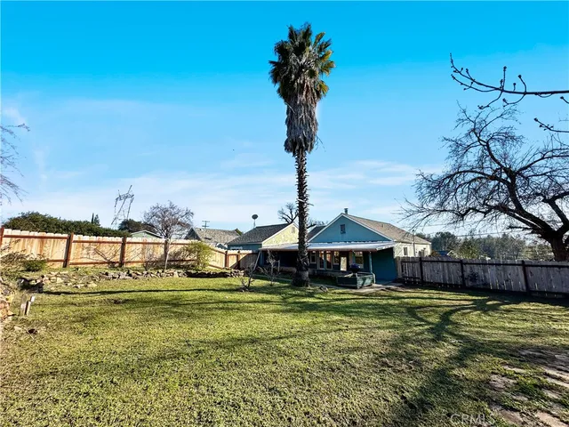 a view of backyard with large trees and wooden fence