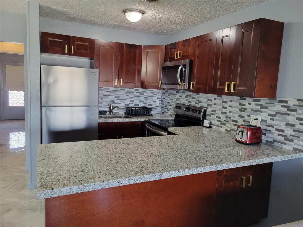 800 Southwest 11th Avenue, Unit 17 Hallandale Beach, FL 33009 - Photo 2 of 18 a kitchen with granite countertop stainless steel appliances and wooden cabinets