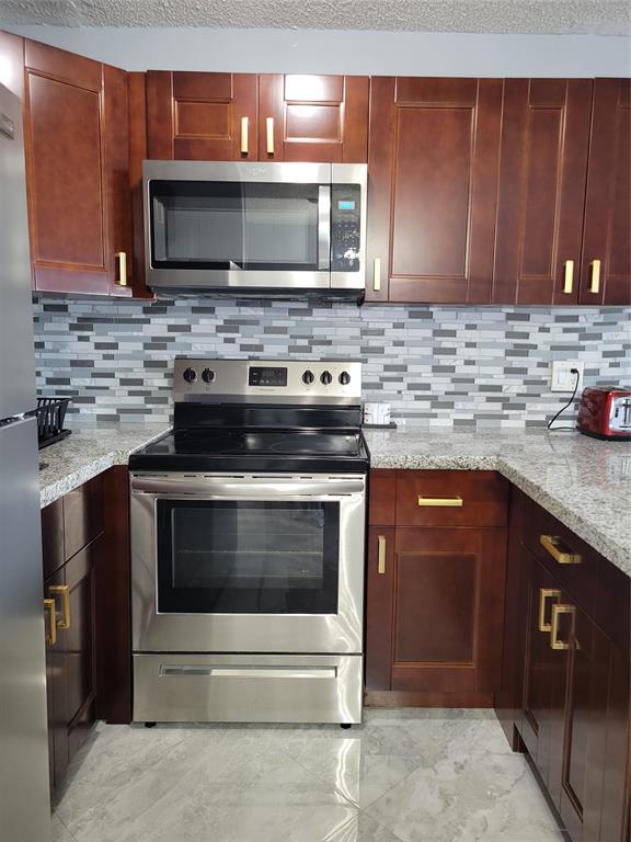 800 Southwest 11th Avenue, Unit 17 Hallandale Beach, FL 33009 - Photo 3 of 18 a kitchen with granite countertop wooden cabinets and stainless steel appliances