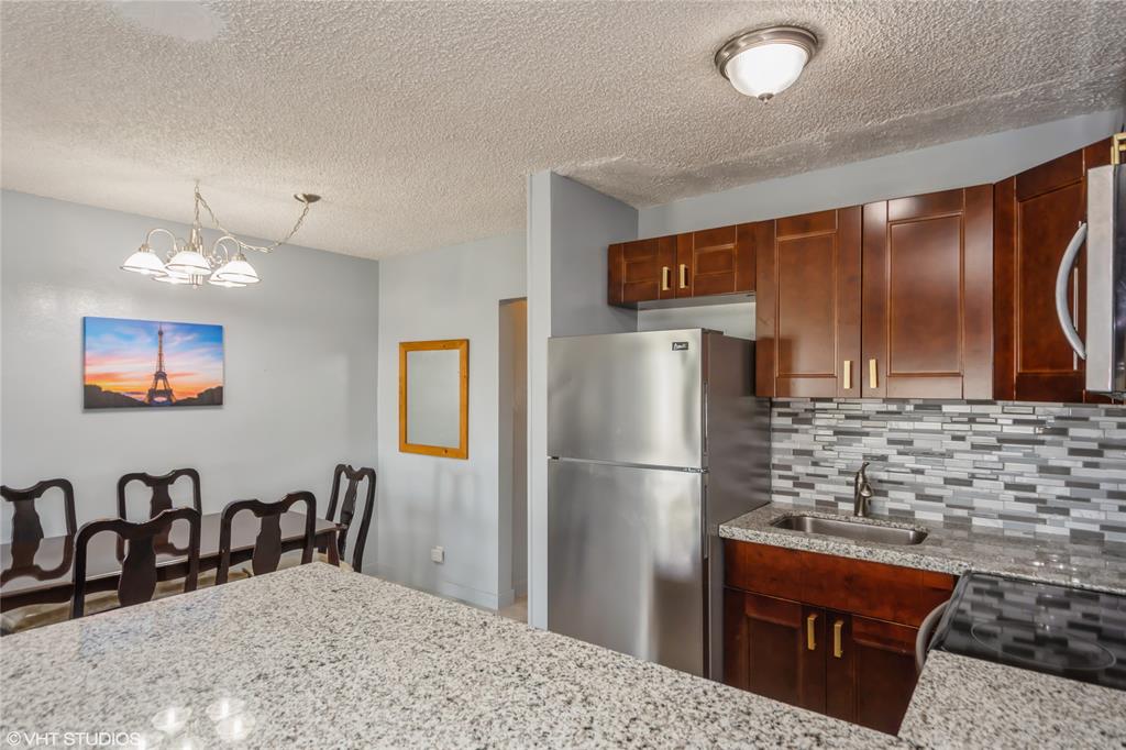 800 Southwest 11th Avenue, Unit 17 Hallandale Beach, FL 33009 - Photo 5 of 18 a kitchen with stainless steel appliances granite countertop a refrigerator a stove and a sink with wooden floor