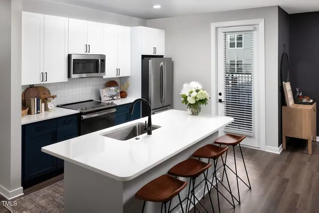 a kitchen with stainless steel appliances a dining table chairs and refrigerator