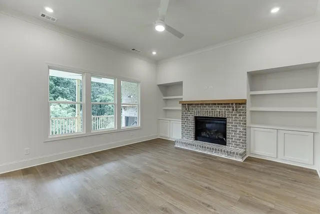 a view of an empty room with wooden floor fireplace and a window