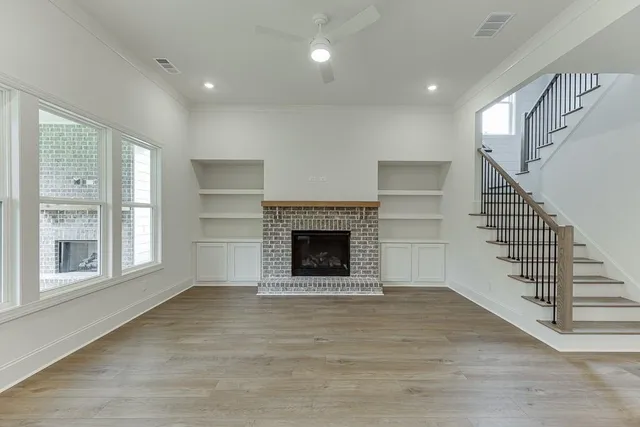 a view of an empty room with wooden floor fireplace and a window