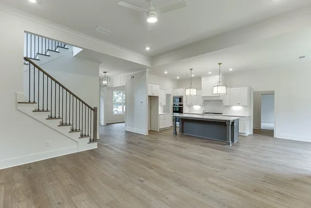 a large kitchen with stainless steel appliances granite countertop a large counter top a stove and a wooden floors