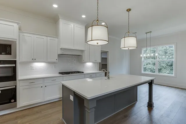 a kitchen with stainless steel appliances kitchen island granite countertop a stove a sink a center island and cabinets