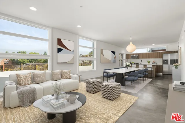 a living room with furniture kitchen view and large windows