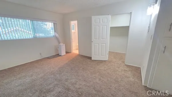 a view of an empty room with closet and a window