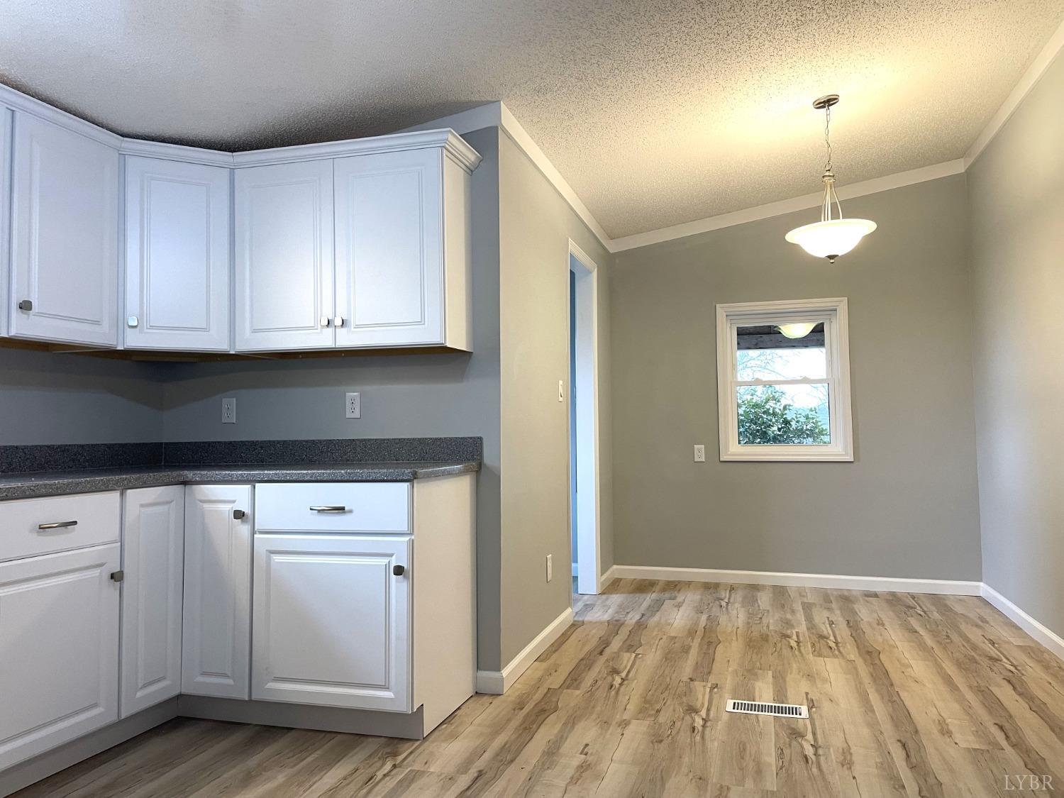 232 Camp Branch Road Gretna, VA 24557 - Photo 18 of 47 a kitchen with granite countertop a stove a sink and white cabinets with wooden floor