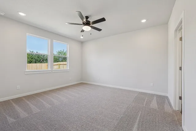 an empty room with windows and fan