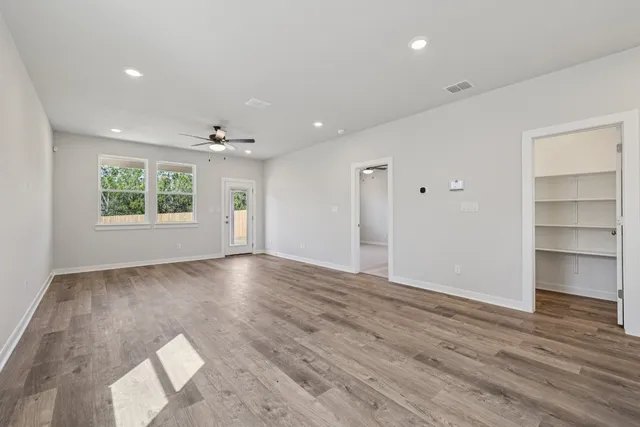 a view of an empty room with a window and wooden floor