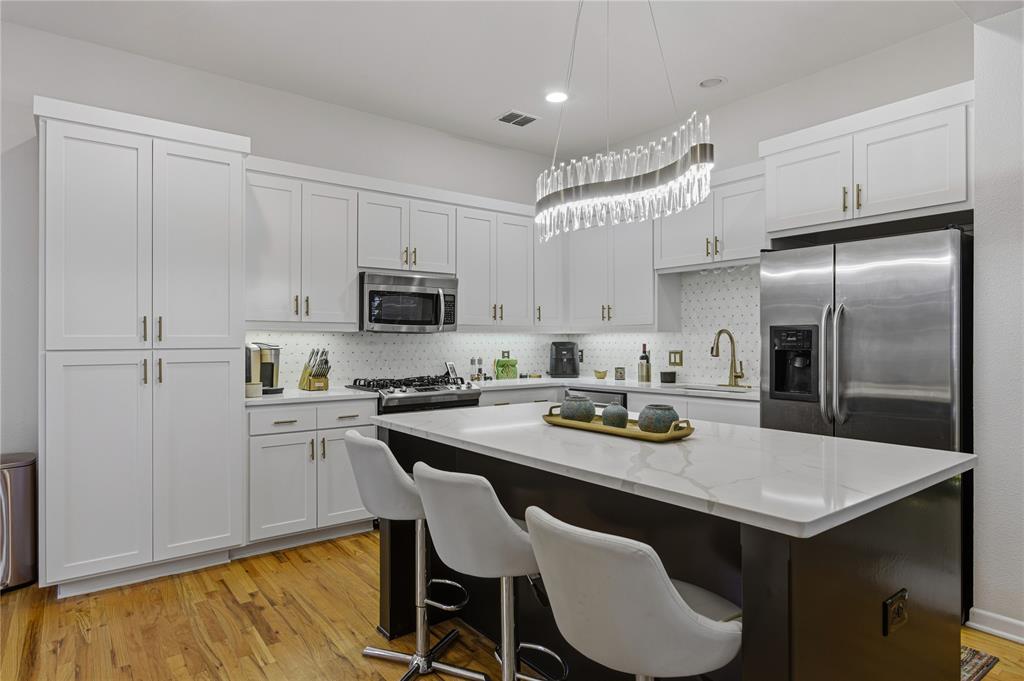 6269 Oram Street, Unit 23 Dallas, TX 75214 - Photo 13 of 39 a kitchen with a sink a kitchen island and stainless steel appliances