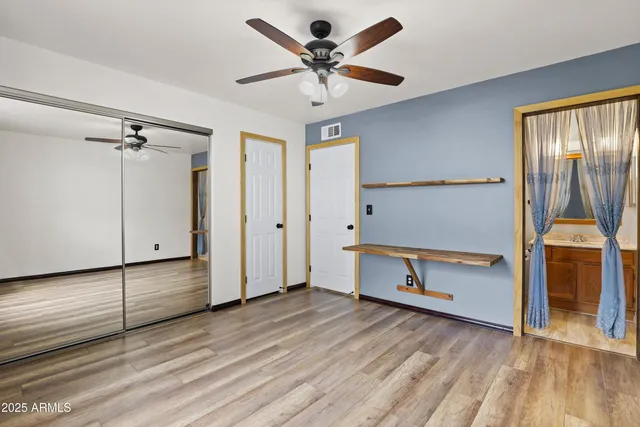 a view of an empty room with window and wooden floor