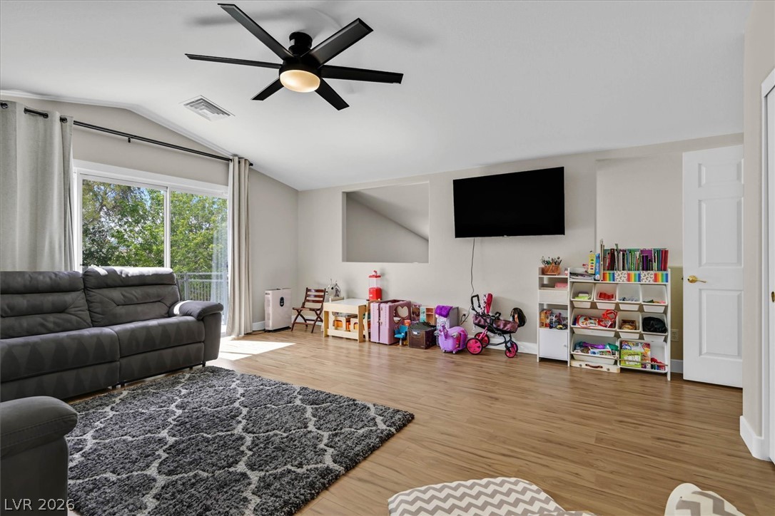 1259 Moon Vision Street Henderson, NV 89052 - Photo 25 of 53 A casual living space features wood-toned flooring and a spacious glass slider for outdoor access.
