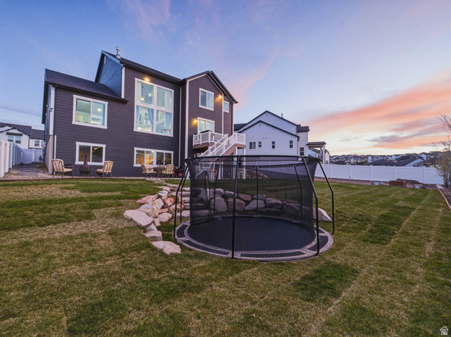 2487 Canyon Wild Road, Unit 413 Draper, UT 84020 - Photo 67 of 75 Back of house at dusk featuring a fenced backyard and a trampoline